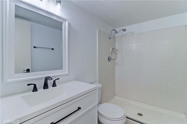 bathroom featuring toilet, a tile shower, and vanity