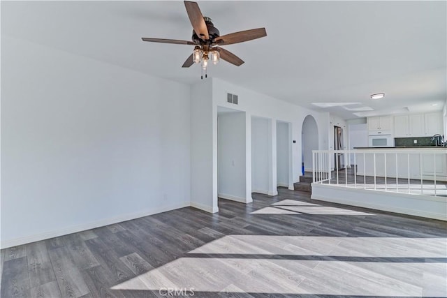 unfurnished living room with ceiling fan and wood-type flooring