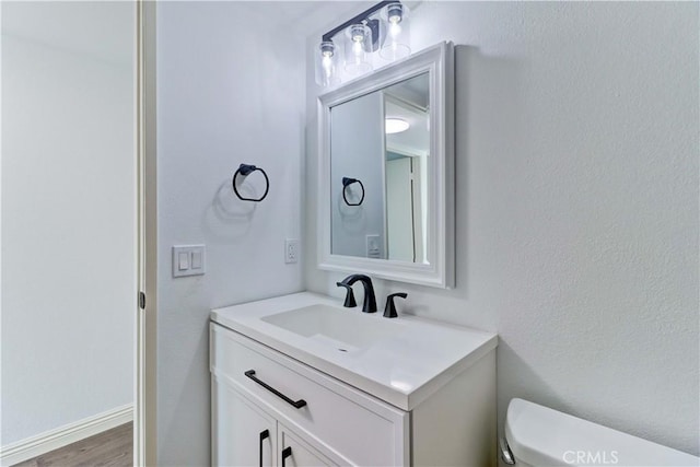 bathroom featuring toilet, wood-type flooring, and vanity