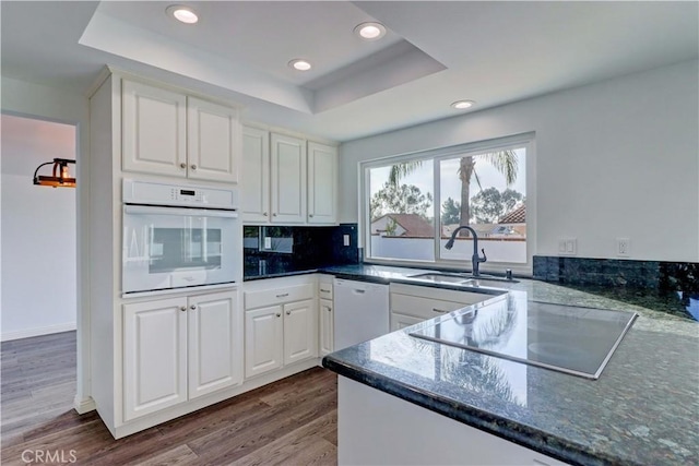 kitchen featuring sink, white cabinets, a raised ceiling, and white appliances