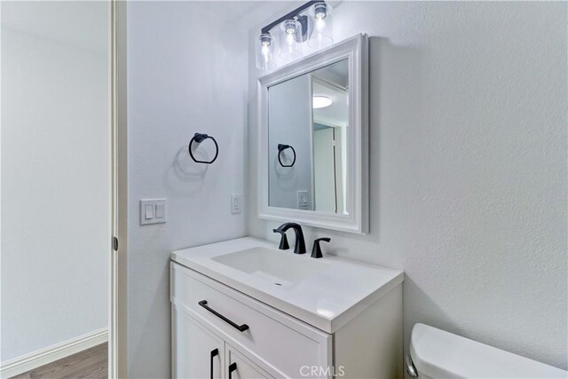 bathroom featuring toilet, hardwood / wood-style flooring, and vanity