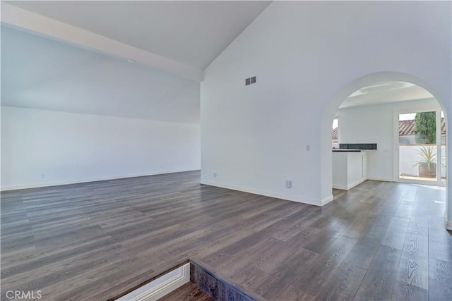 empty room with dark hardwood / wood-style flooring and high vaulted ceiling