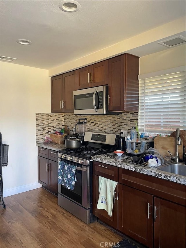 kitchen featuring hardwood / wood-style floors, backsplash, sink, dark brown cabinets, and stainless steel appliances