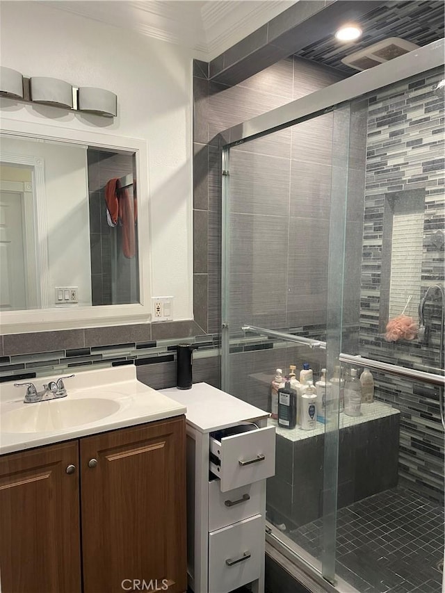 bathroom featuring vanity, a shower with door, ornamental molding, and tasteful backsplash