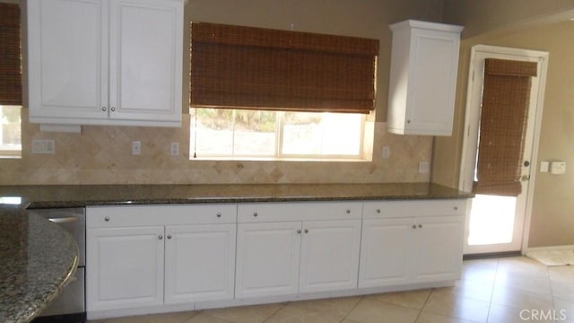 kitchen featuring white cabinets, light tile patterned flooring, dark stone counters, and tasteful backsplash