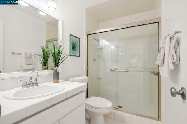 bathroom with tile patterned floors, a shower with door, vanity, and toilet