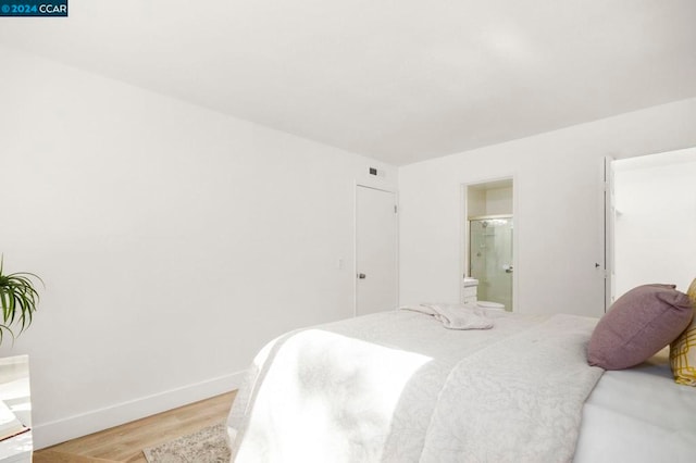 bedroom with light hardwood / wood-style floors and ensuite bath