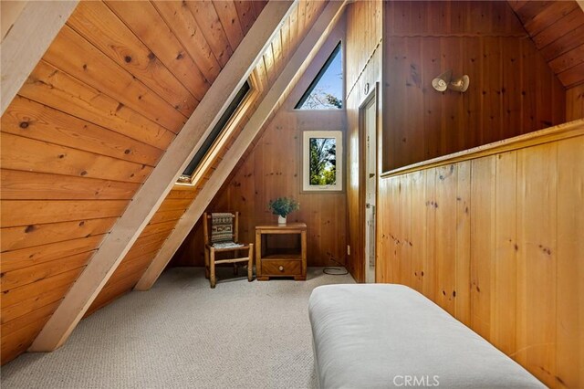 additional living space with carpet flooring, lofted ceiling with skylight, wooden ceiling, and wood walls