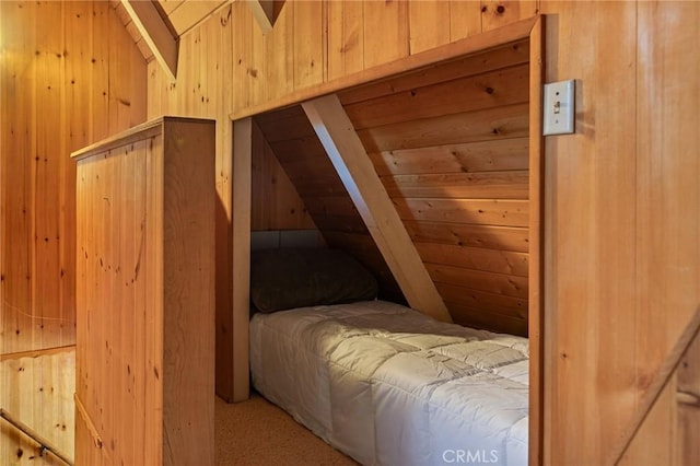 carpeted bedroom featuring lofted ceiling and wood walls