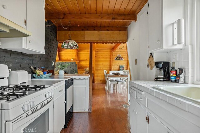 kitchen with beamed ceiling, white gas range oven, white cabinetry, and dark wood-type flooring