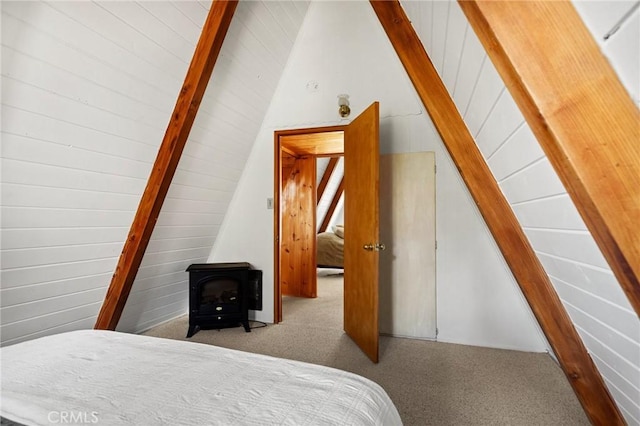 carpeted bedroom with beamed ceiling, high vaulted ceiling, and a wood stove