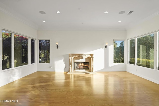 unfurnished living room featuring a wealth of natural light, crown molding, and light hardwood / wood-style flooring