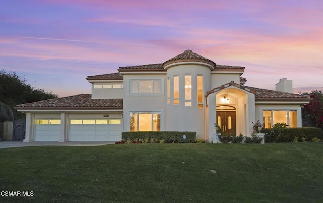 mediterranean / spanish-style home with a garage and a lawn