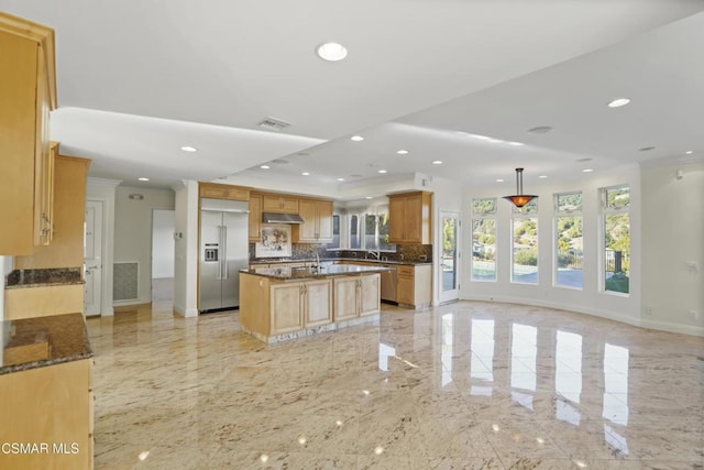 kitchen featuring stainless steel built in fridge, decorative light fixtures, a kitchen island with sink, backsplash, and crown molding