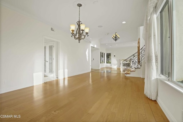 unfurnished living room with an inviting chandelier and wood-type flooring