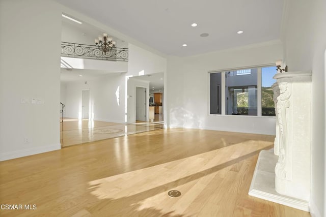 empty room with a fireplace, lofted ceiling, wood-type flooring, crown molding, and a notable chandelier