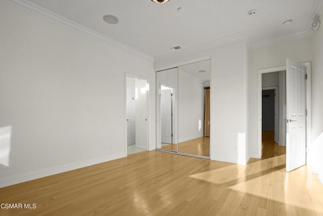 unfurnished bedroom featuring a closet, light hardwood / wood-style floors, and crown molding