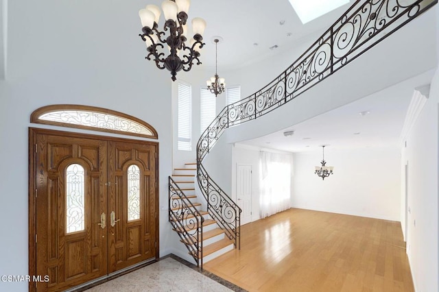 foyer entrance featuring a towering ceiling, a notable chandelier, and crown molding