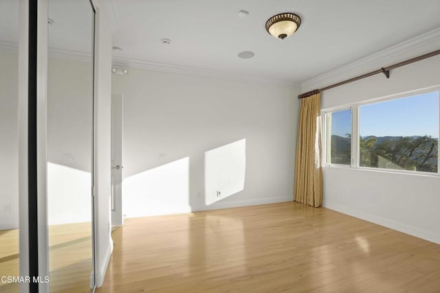 empty room with light wood-type flooring and crown molding