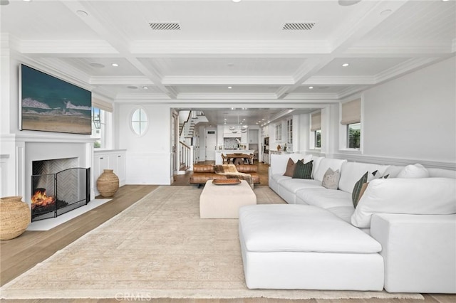 living room with hardwood / wood-style floors, beamed ceiling, coffered ceiling, and ornamental molding