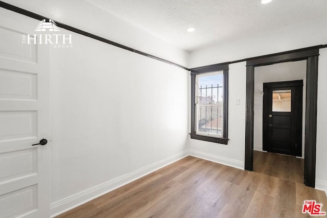 spare room featuring wood-type flooring and a textured ceiling