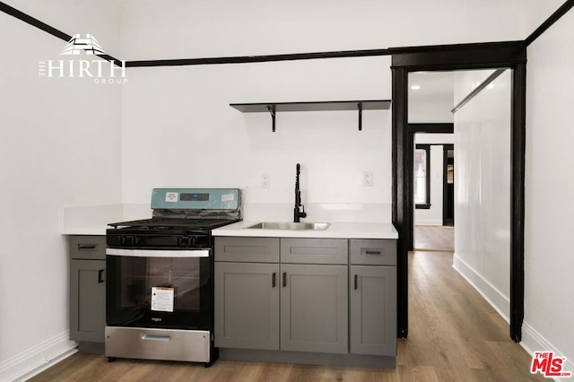 kitchen featuring sink, light hardwood / wood-style floors, gray cabinetry, and stainless steel range oven