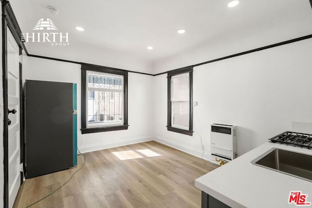 kitchen with heating unit, light hardwood / wood-style flooring, and sink