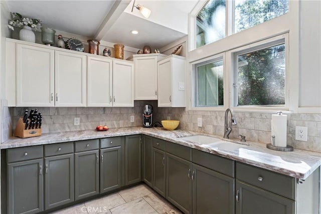 kitchen with white cabinets, sink, decorative backsplash, gray cabinets, and light stone counters