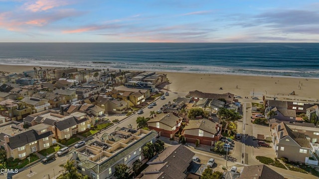 aerial view at dusk with a water view and a beach view