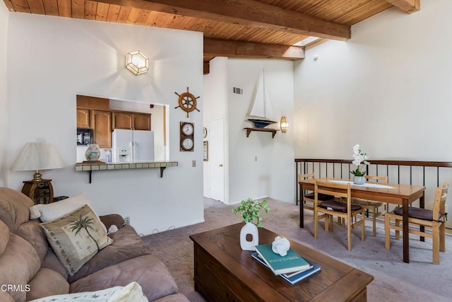 living room with beamed ceiling, light colored carpet, wood ceiling, and a high ceiling