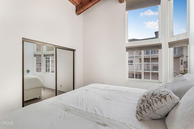 bedroom featuring beam ceiling, carpet floors, high vaulted ceiling, and a closet