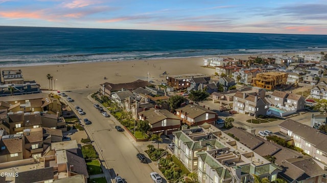 aerial view at dusk with a beach view and a water view