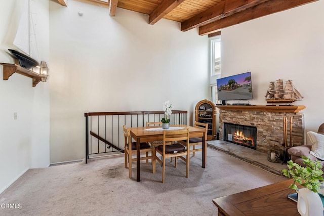 carpeted dining space featuring beam ceiling, wood ceiling, and a fireplace