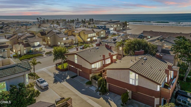 aerial view at dusk with a water view and a view of the beach