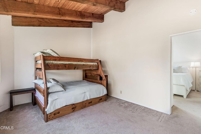 bedroom featuring beam ceiling, light carpet, and wooden ceiling