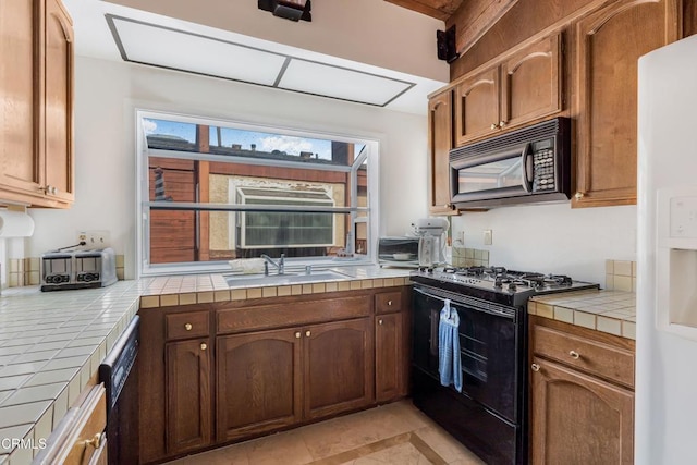 kitchen featuring tile countertops, sink, light tile patterned flooring, and black appliances