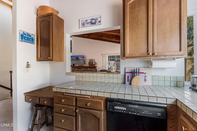 kitchen featuring tile counters, kitchen peninsula, black dishwasher, and vaulted ceiling