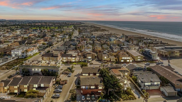 aerial view at dusk with a water view and a beach view