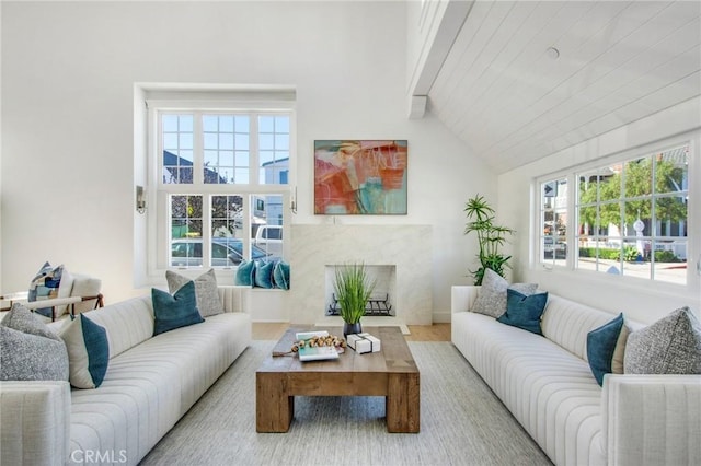 living room featuring a high end fireplace, wood-type flooring, and vaulted ceiling