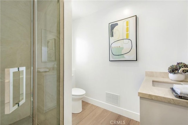 bathroom with an enclosed shower, vanity, toilet, and wood-type flooring