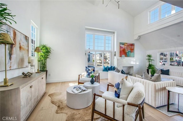 living room featuring a high ceiling, light hardwood / wood-style flooring, and a wealth of natural light