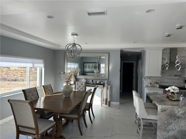 dining space featuring baseboards, visible vents, a raised ceiling, marble finish floor, and an inviting chandelier