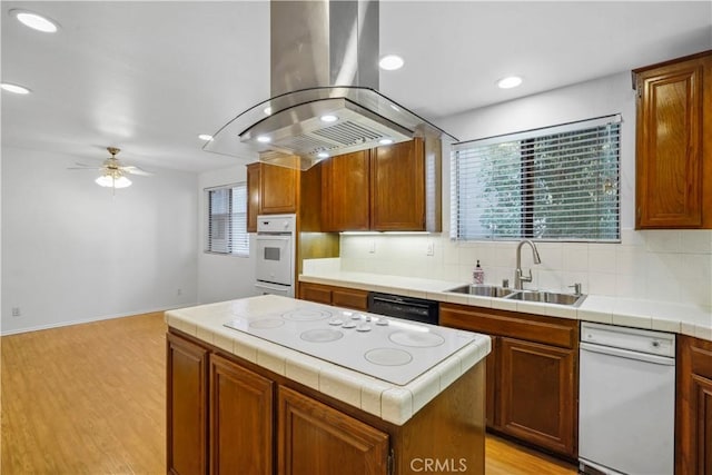 kitchen with sink, tasteful backsplash, island range hood, a kitchen island, and white appliances