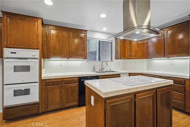 kitchen with a kitchen island, island range hood, sink, white appliances, and light hardwood / wood-style flooring