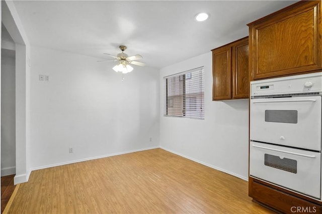 kitchen featuring ceiling fan, light wood-type flooring, and double oven