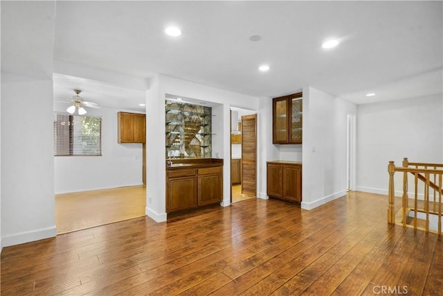 unfurnished living room with ceiling fan, wood-type flooring, and sink