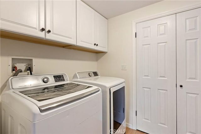 clothes washing area with cabinets and washer and dryer