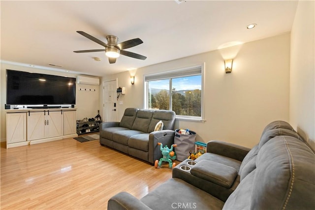 living room with an AC wall unit, ceiling fan, and light wood-type flooring