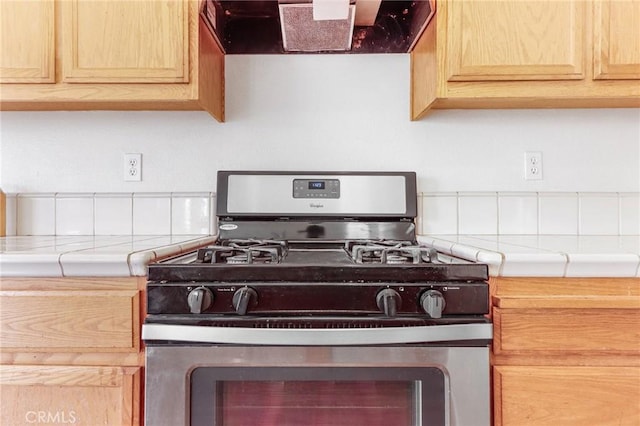 kitchen with light brown cabinetry, gas stove, tile counters, and exhaust hood