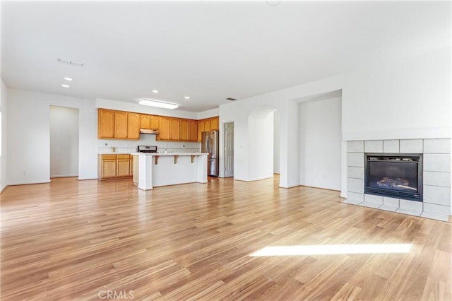 unfurnished living room with a tiled fireplace and light hardwood / wood-style floors